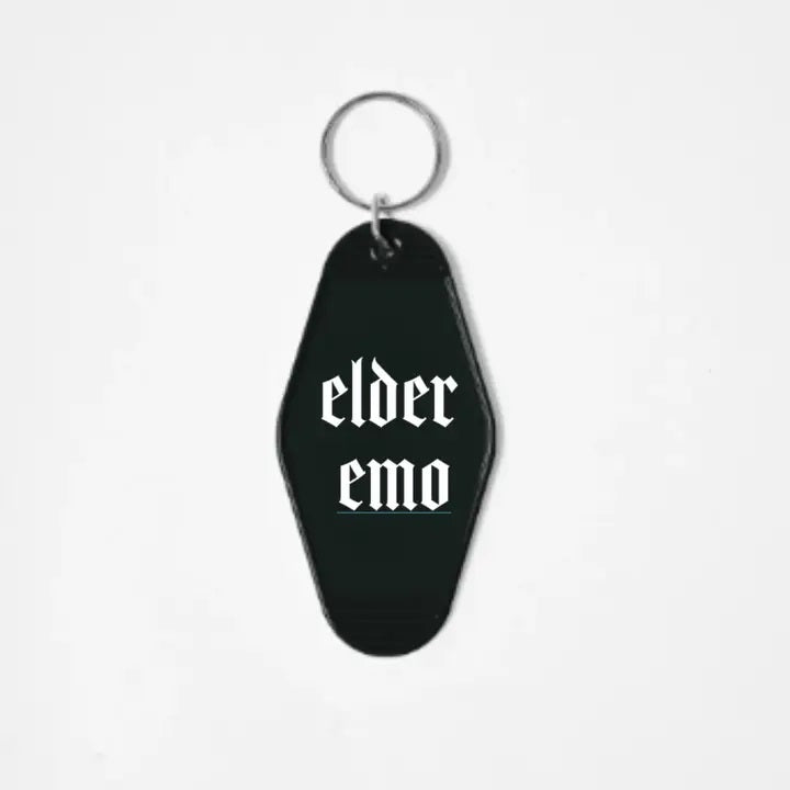 A black keychain shaped like a motel tag with the words "Elder Emo" written in a white gothic font